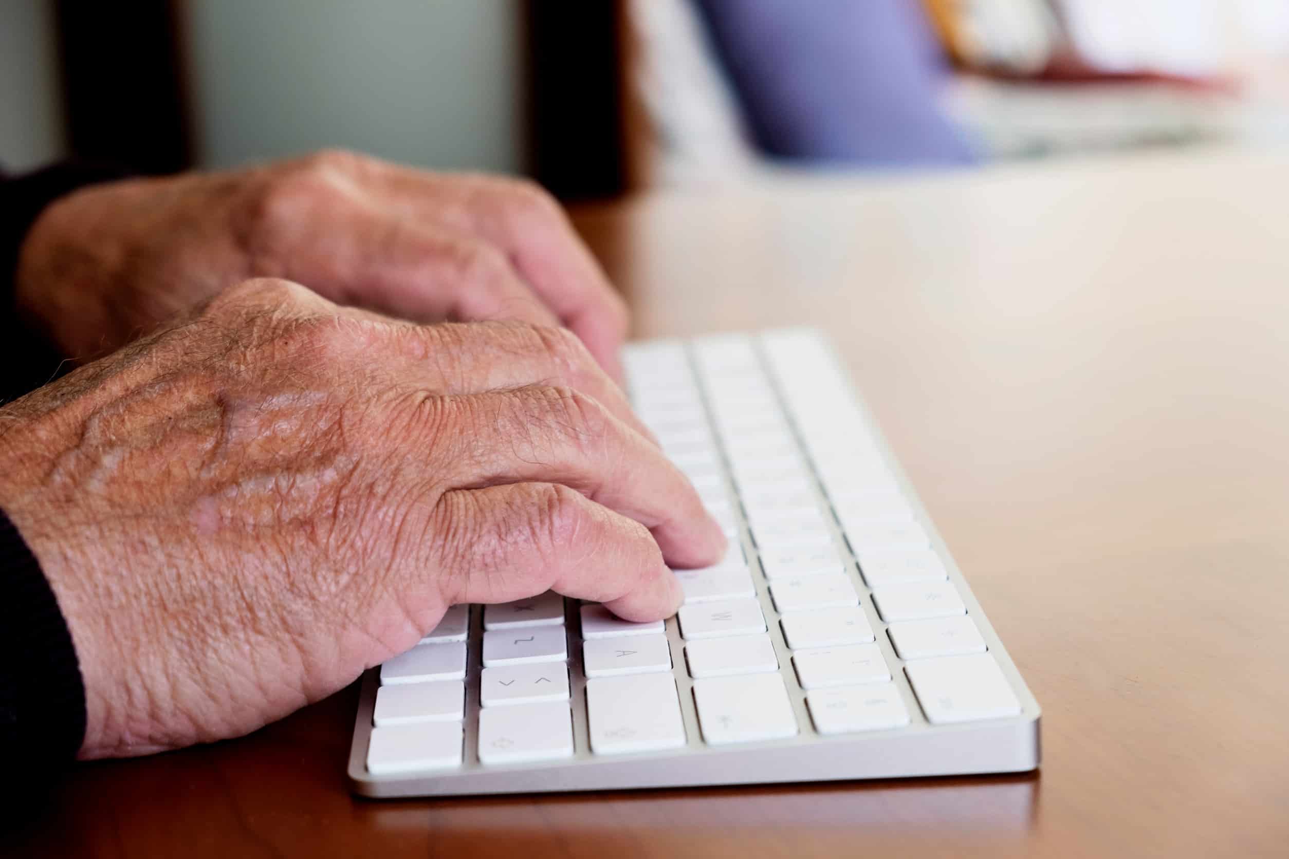 Older adult typing on keyboard