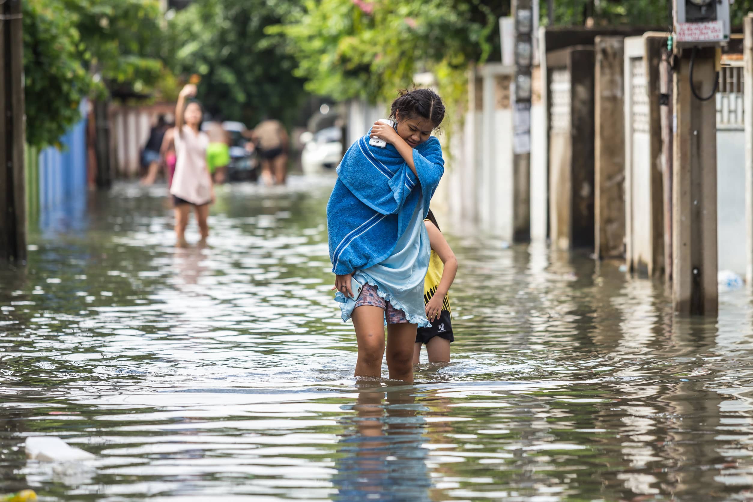 Woman and child walking through flooded street.