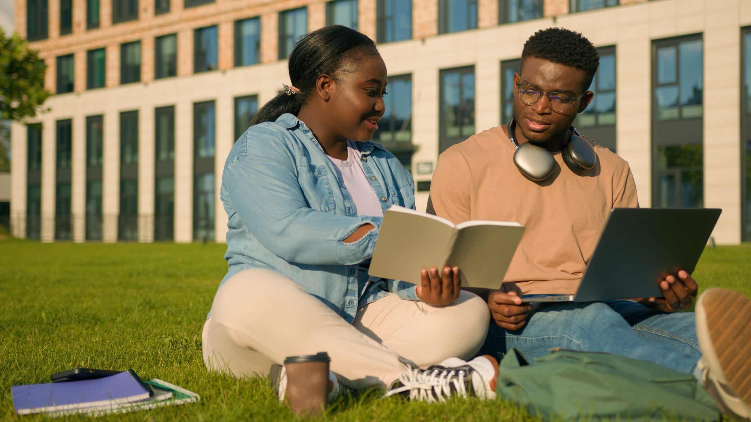 Two college students sit together on campus green