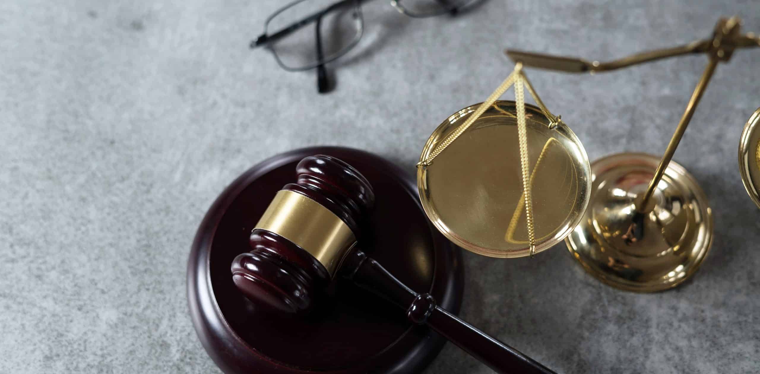 Gavel, scales and glasses on grey background