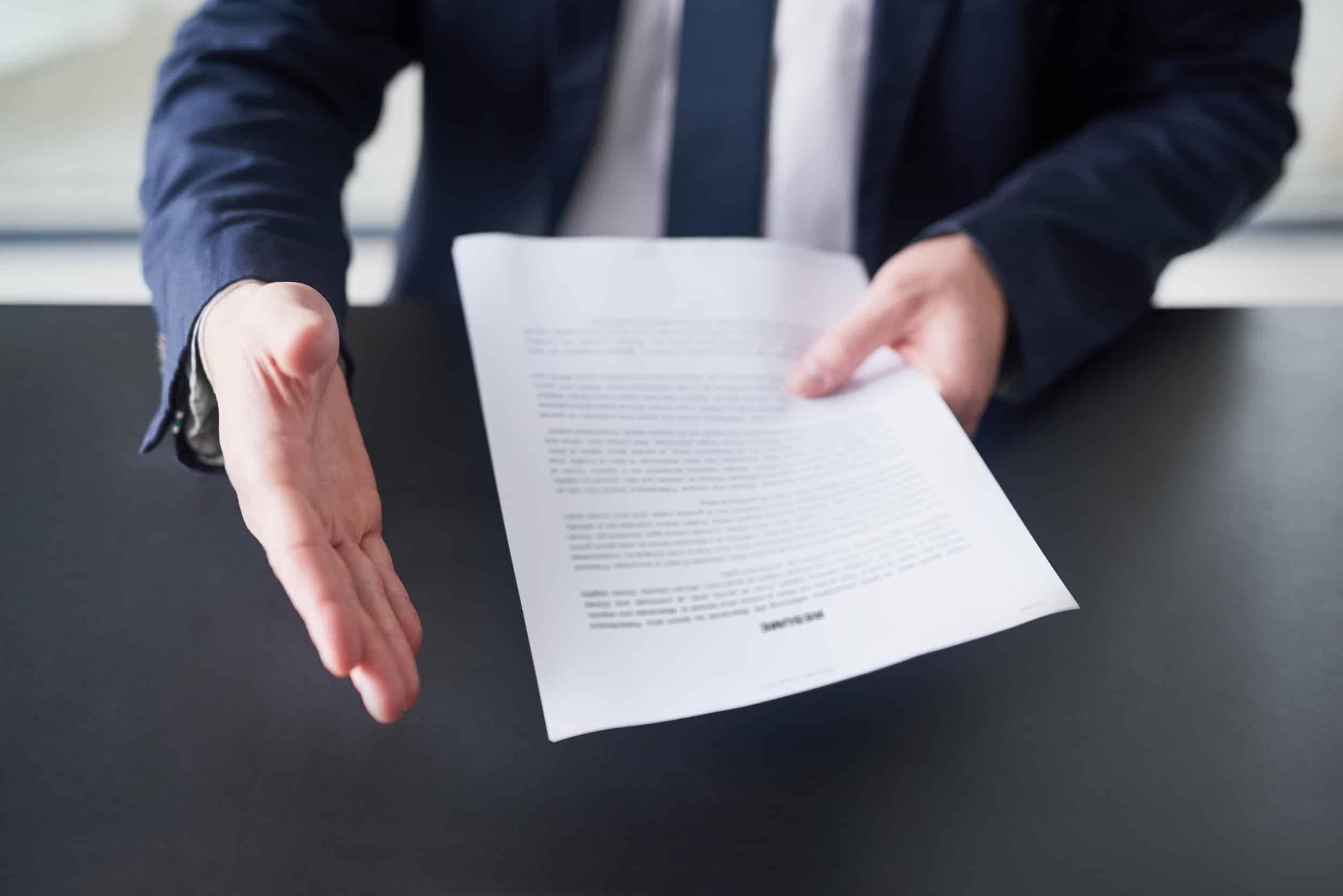 Cropped shot of a businessman holding a resume and extending his arm to shake hands.