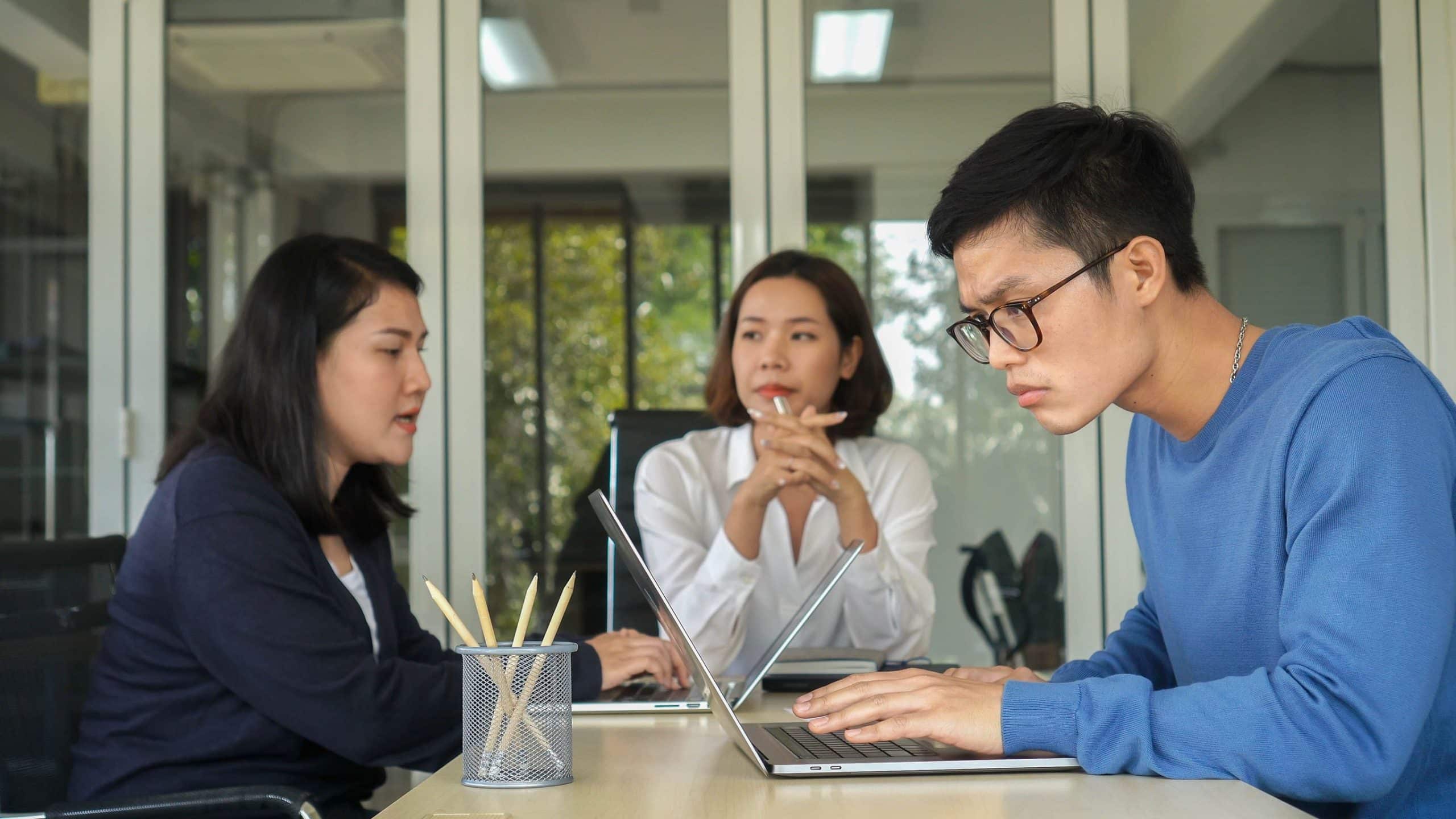 Group of employees working on laptop in office