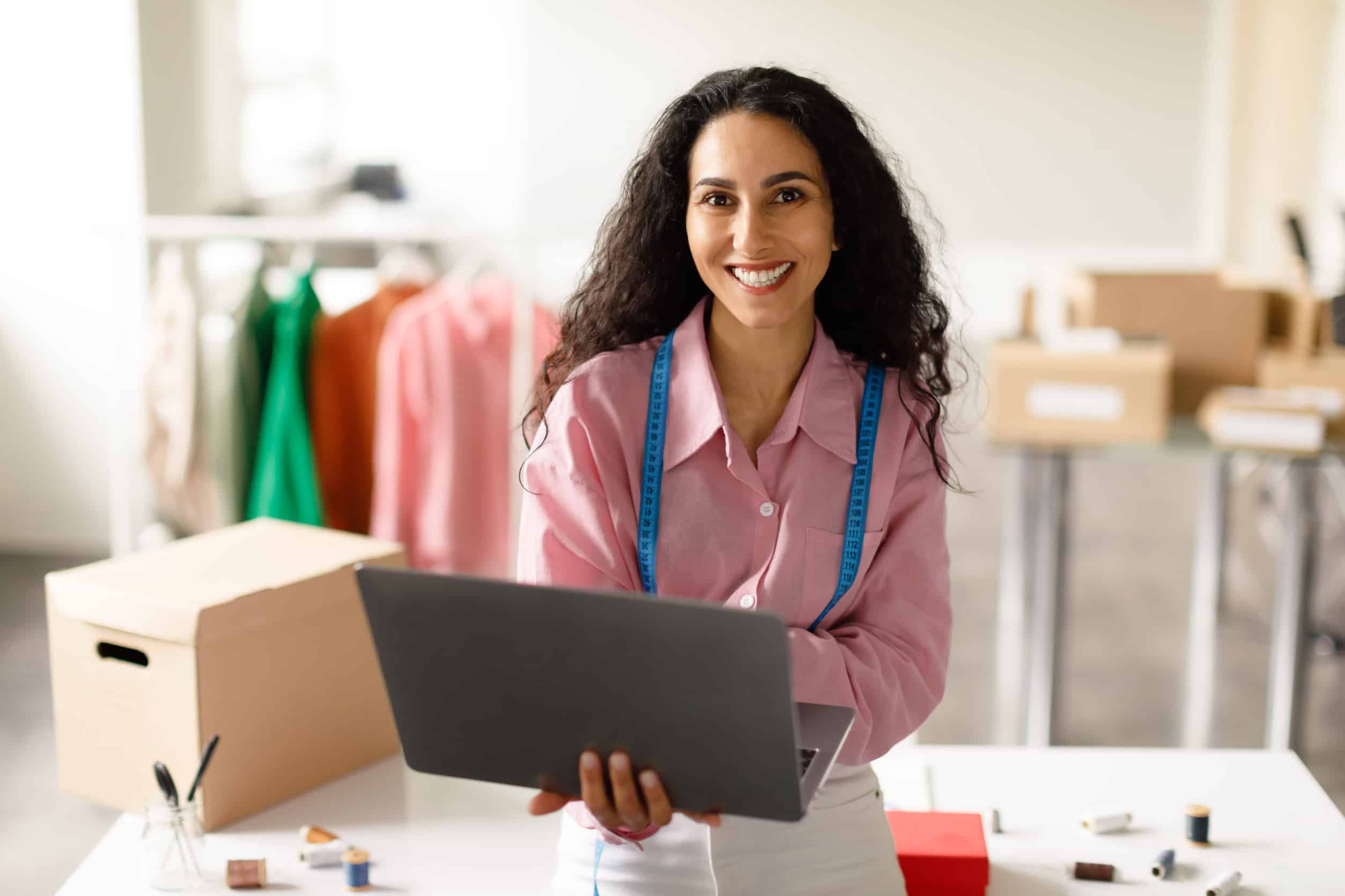 Fashion Designer Woman Working On Laptop Computer In Clothing Showroom