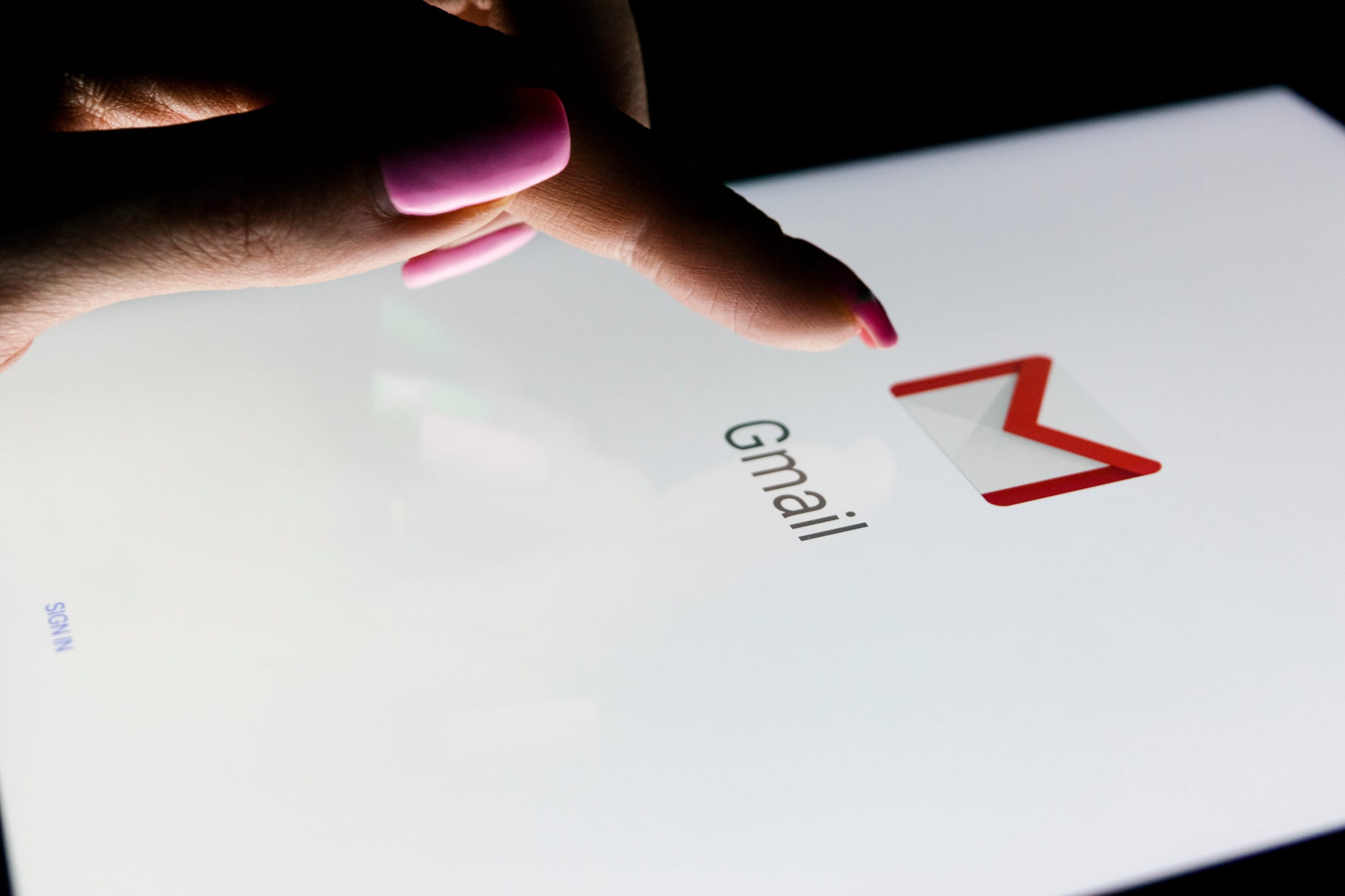 A woman's hand is touching screen on tablet at night with open Google Gmail application.